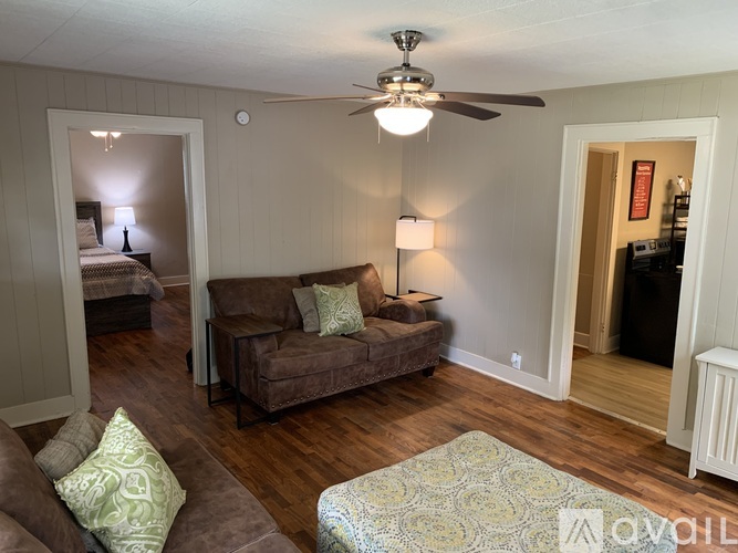 A living room with a brown couch and a ceiling fan.