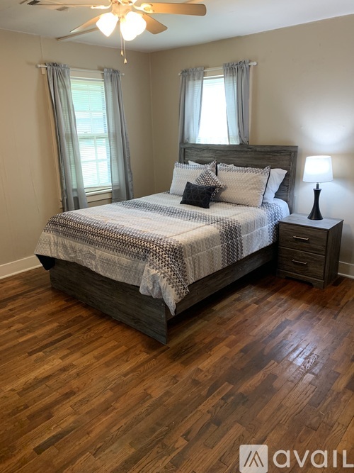 A bedroom with a large bed and wooden flooring.