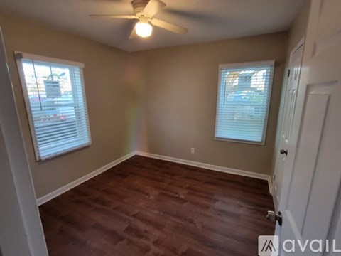 A room with a ceiling fan and two windows.