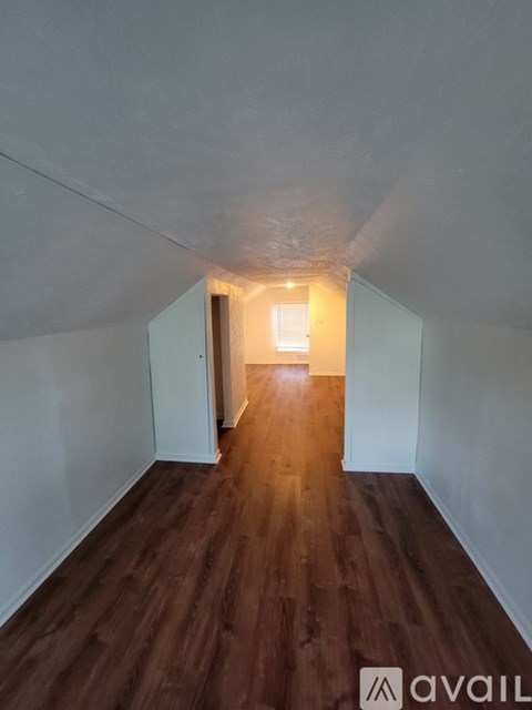 A long hallway with wood floors and white walls.