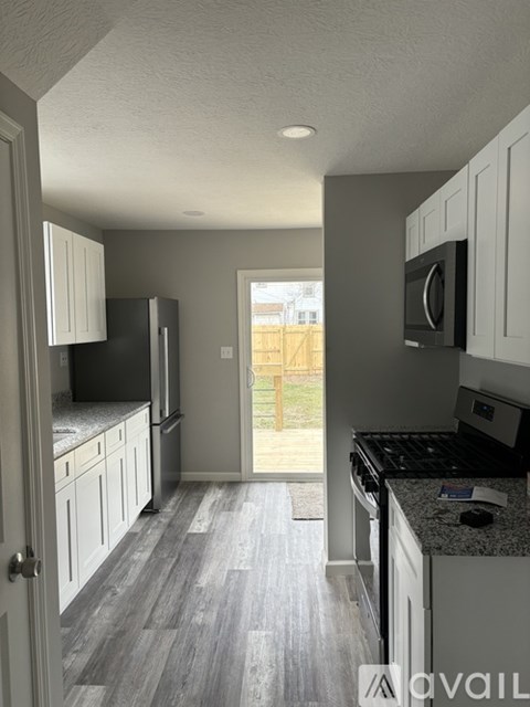 A kitchen with white cabinets and a black fridge.