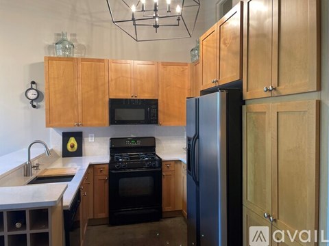 A kitchen with wooden cabinets and a black refrigerator.