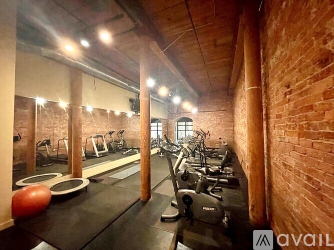A gym with a brick wall and a row of treadmills.