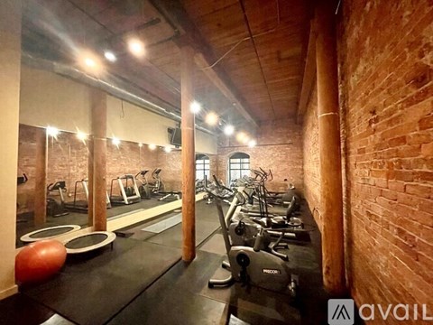 A gym with a brick wall and a row of treadmills.