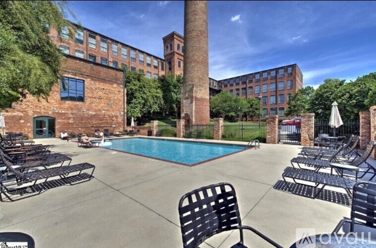 A pool area with chairs and a tall brick chimney.