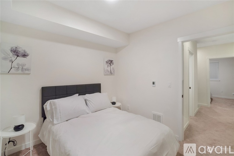 A bedroom with a large bed and two framed pictures on the wall.