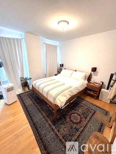 A bedroom with a large bed and a rug on the floor.