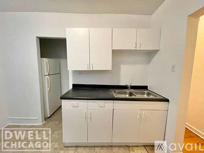 A kitchen with white cabinets and a black countertop.