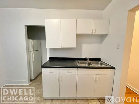 A kitchen with white cabinets and a black countertop.