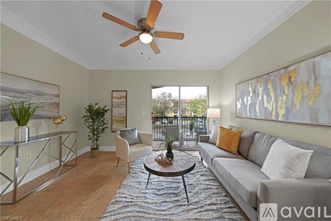 A living room with a grey couch, a coffee table, a ceiling fan, and a painting on the wall.