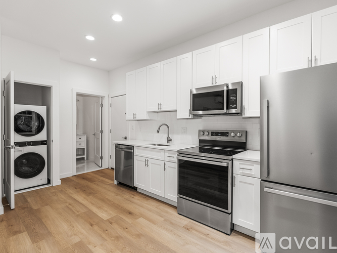 A modern kitchen with stainless steel appliances and wooden flooring.
