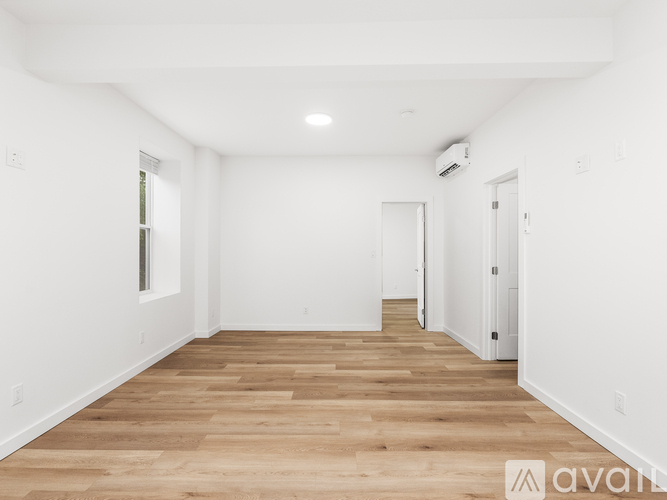 A spacious room with wooden flooring and white walls.