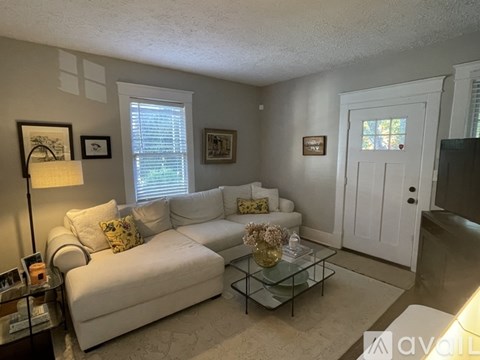 A living room with a white couch and a glass coffee table.