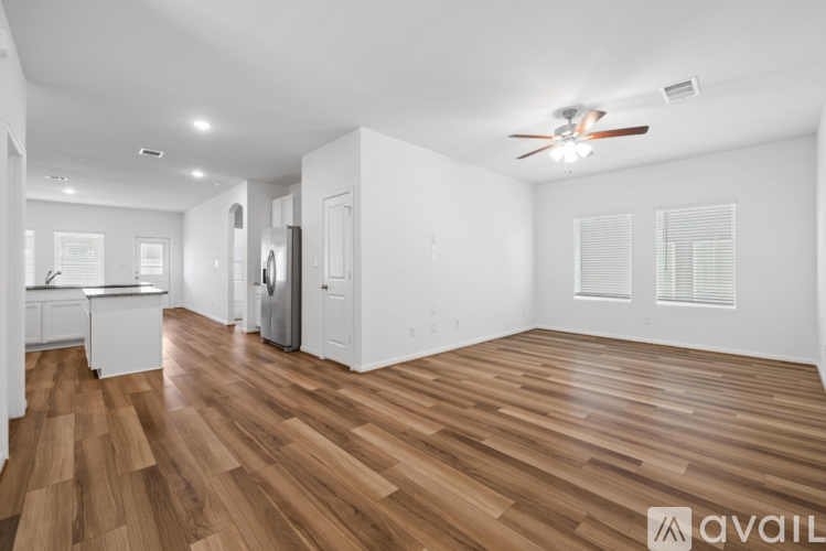 A spacious room with wooden flooring and a ceiling fan.