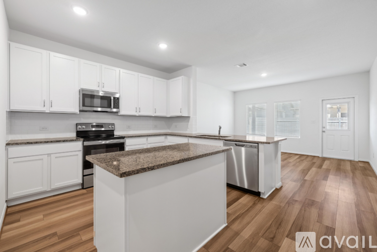 A kitchen with white cabinets and a brown island.