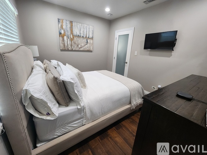 A bedroom with a large bed and a television mounted on the wall.