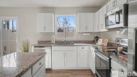 A kitchen with white cabinets and granite countertops.