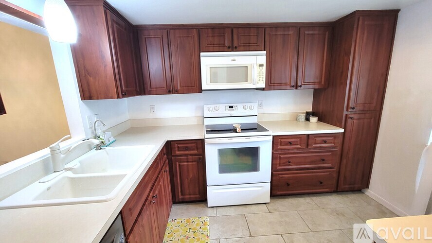 A kitchen with brown cabinets and white appliances.