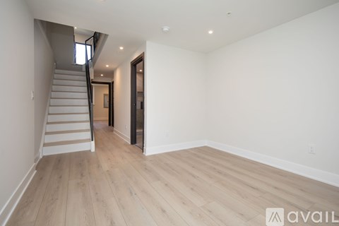 A spacious room with wooden flooring and a staircase leading to another level.