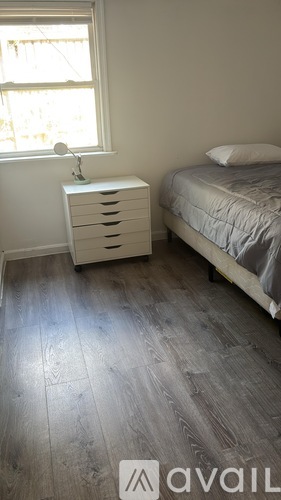 A bedroom with a bed, nightstand, and window.