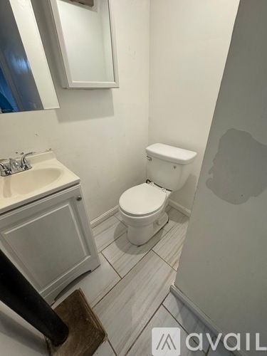 A white toilet in a bathroom with a sink and mirror.