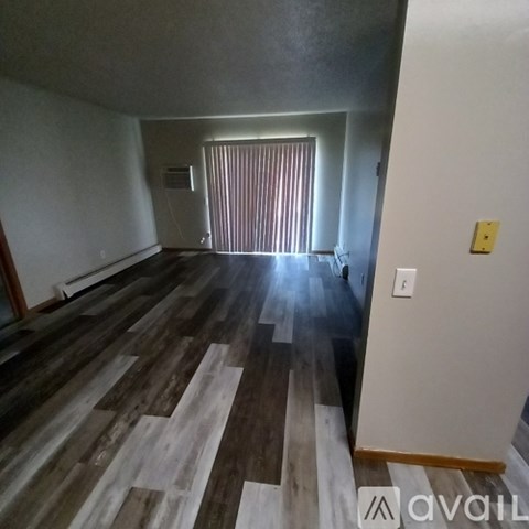 A room with wooden flooring and a window with blinds.