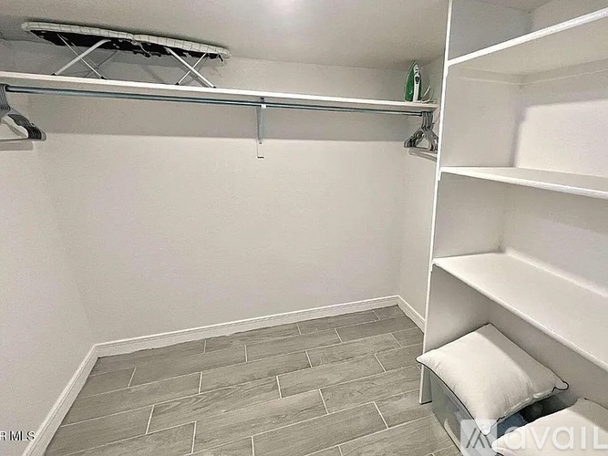 A walk-in closet with a white bench and grey tiled floor.