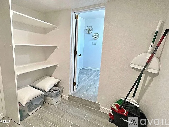 A broom is leaning against a wall in a room with a white door.