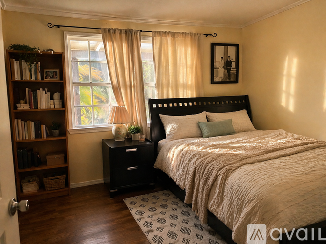 A bedroom with a large bed, a bookshelf, and a window with curtains.