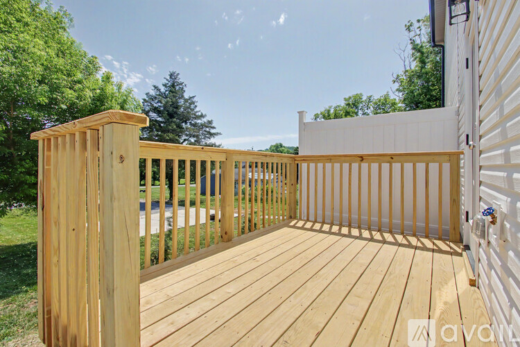 A wooden deck with a white fence and trees in the background.