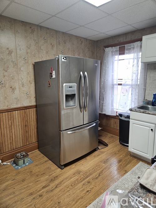 A stainless steel refrigerator with a water and ice dispenser in the middle of the door stands in a kitchen.