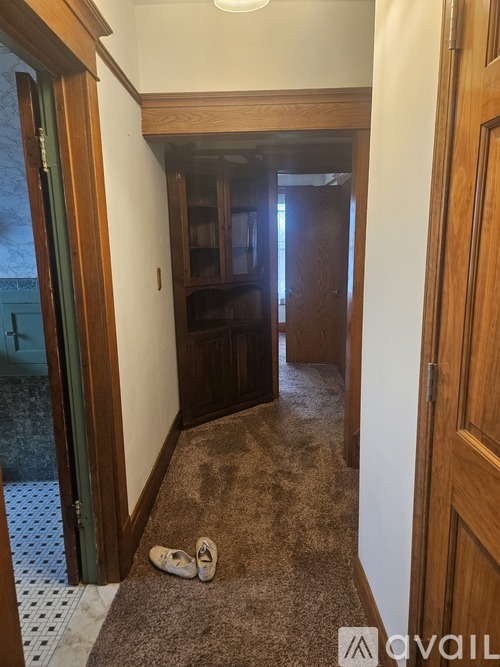 A hallway with a pair of slippers on the carpet.