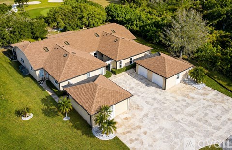 A large house with a brown roof and white walls surrounded by a grassy lawn.