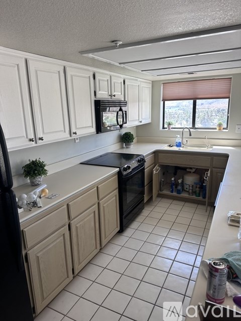 A kitchen with white cabinets and a black refrigerator.