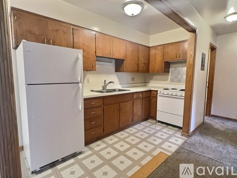 A kitchen with a white fridge, brown cabinets, and a white stove top oven.