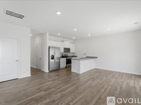 A spacious kitchen with white cabinets and a wooden floor.