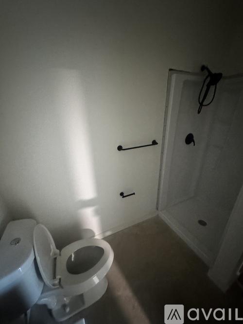 A toilet in a small bathroom with a door and a towel rack.