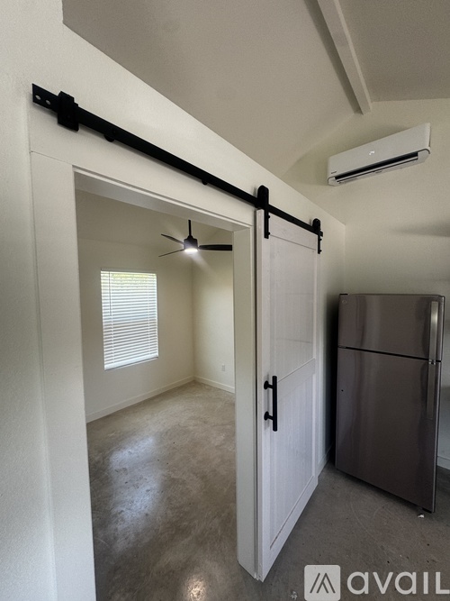 A kitchen area with a refrigerator, a ceiling fan, and a sliding door.