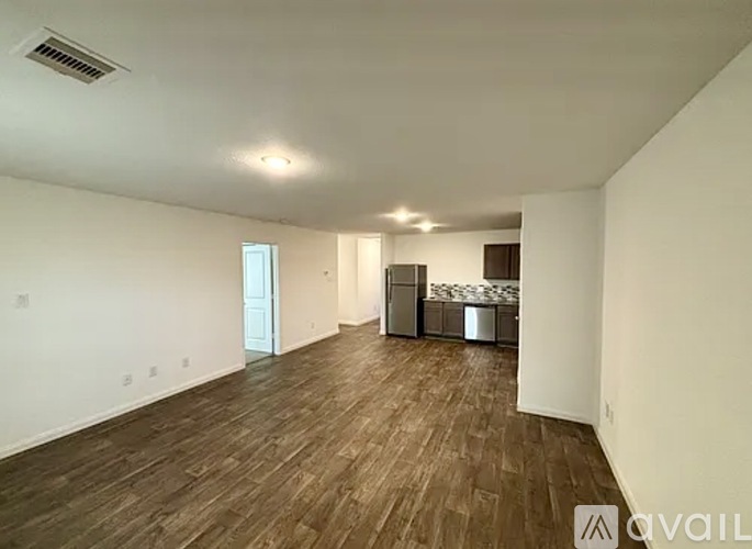 A spacious room with wooden flooring and white walls.