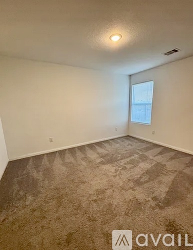 A room with a carpeted floor and a window.