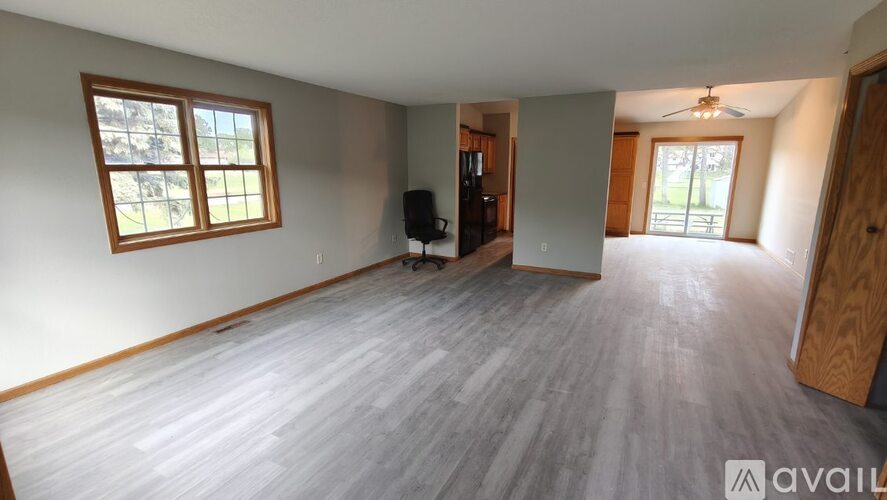 A spacious room with wooden flooring and a ceiling fan.