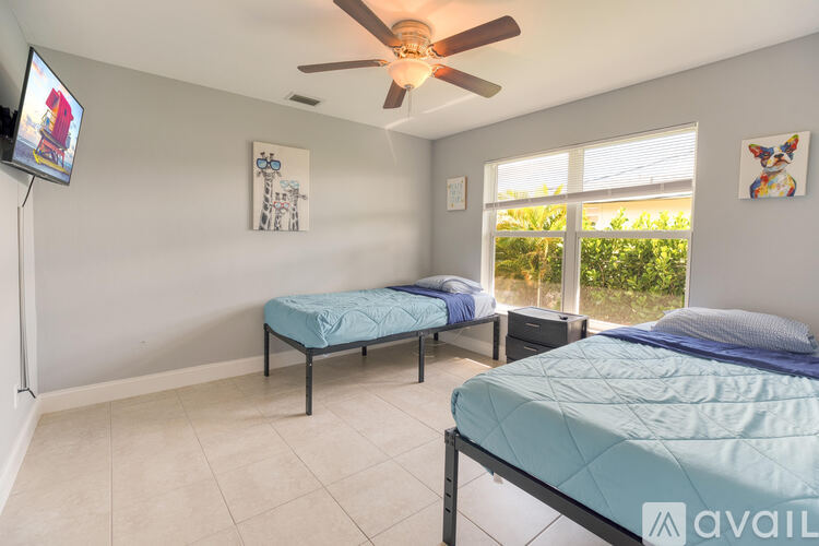 A bedroom with two beds and a ceiling fan.