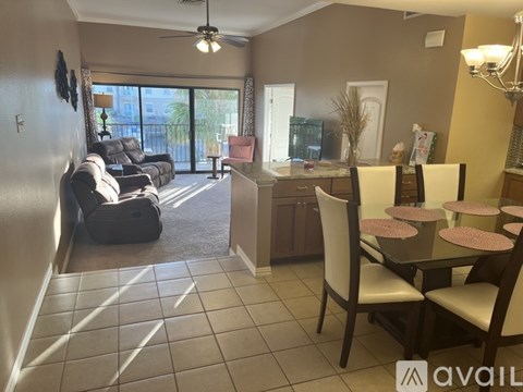 A living room with a black couch and a dining table with chairs.