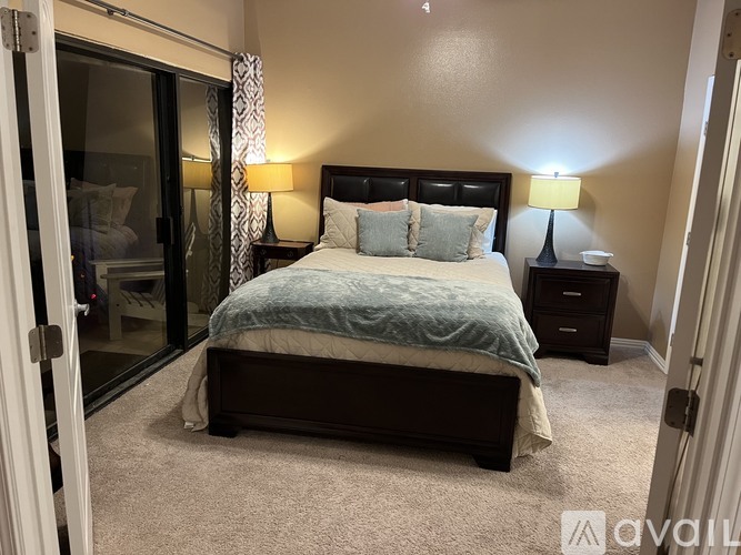A bedroom with a bed, two lamps, and a nightstand.
