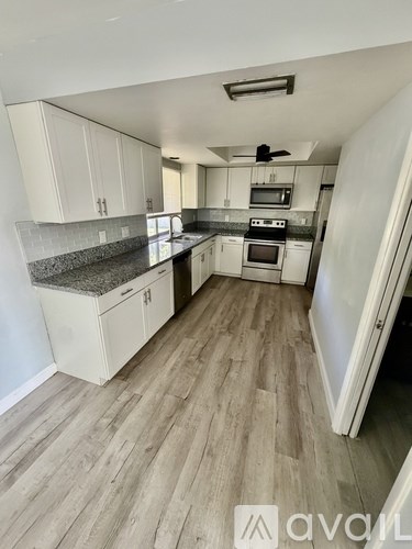 A kitchen with white cabinets and a grey countertop.