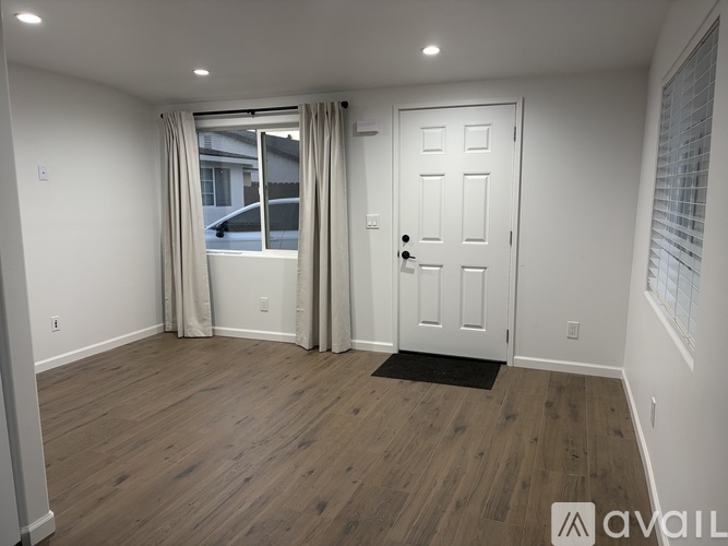 A room with a white door and a window with curtains.