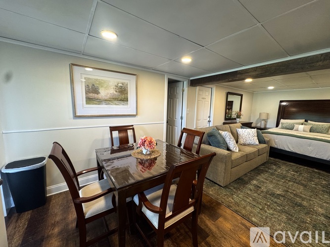 A dining room with a table set for two and a couch in the background.