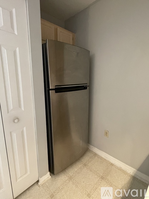A stainless steel refrigerator in a kitchen with a white door.