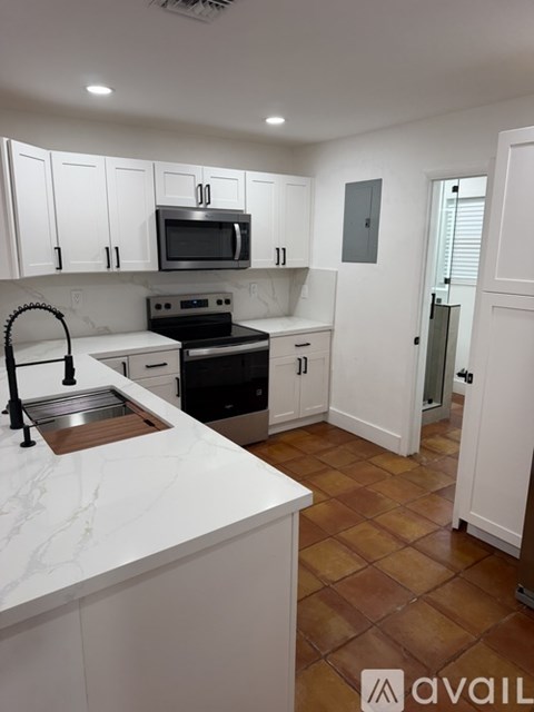 A kitchen with white cabinets and a marble countertop.