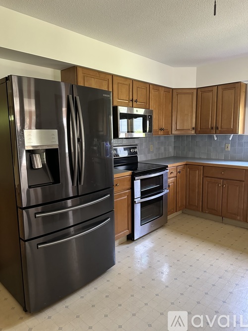 A kitchen with a black fridge and wooden cabinets.
